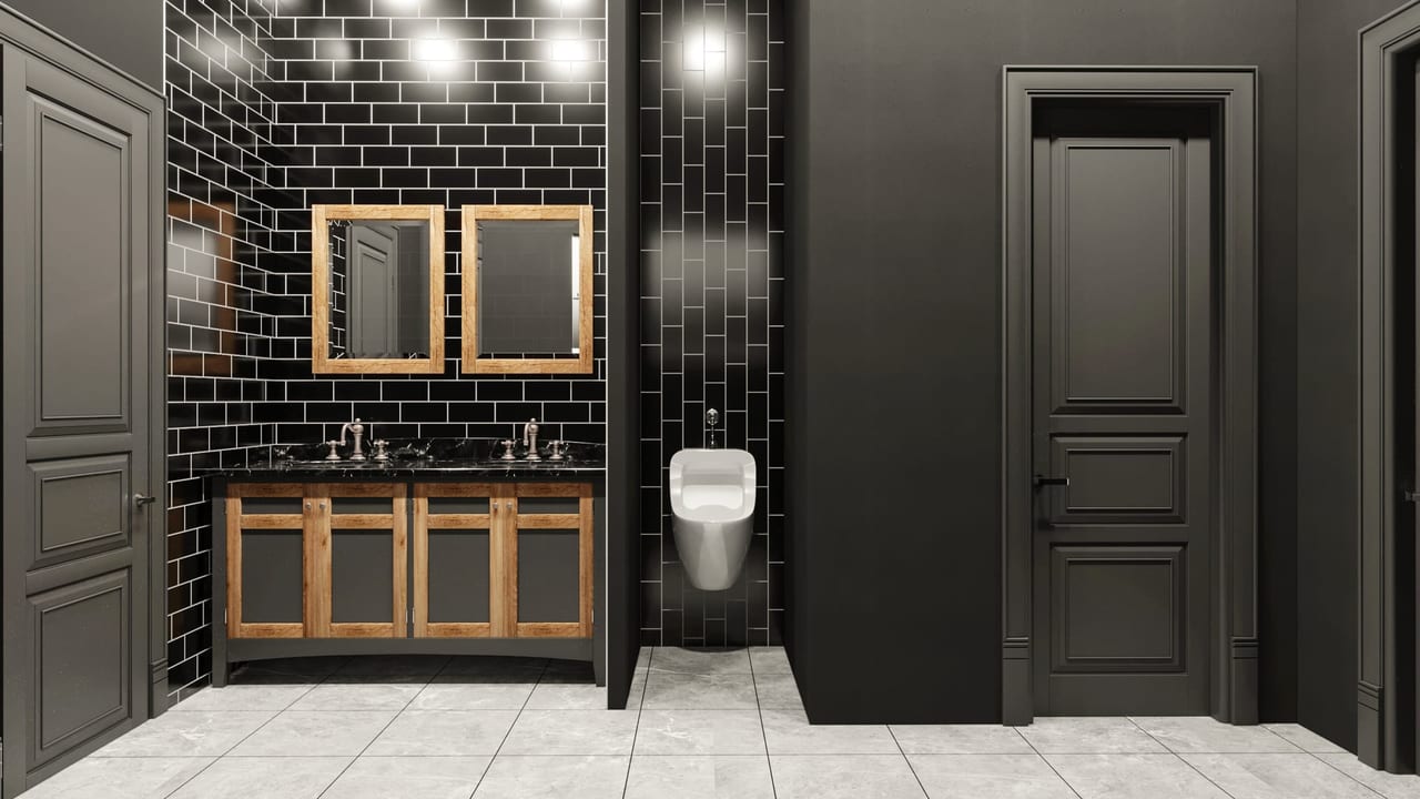 Lavabo hattı: siyah metro fayans, ahşap çerçeveli iki ayna ve koyu mermer tezgâh üzerinde çift lavabo.